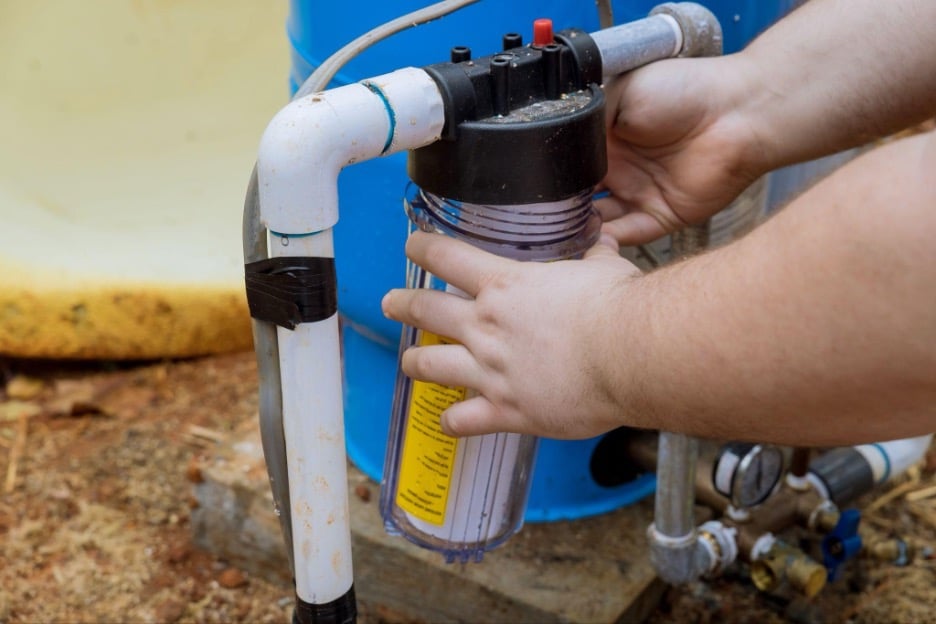 Homeowner performing routine maintenance on a whole house water filtration system for home in Dallas TX. 
