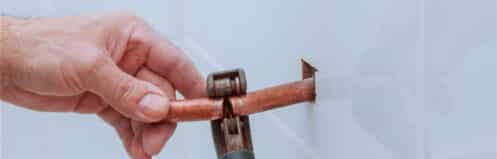 Pinhole leaks in copper pipes from hard-water pitting corrosion, with blue-green staining on a Coppell supply line
