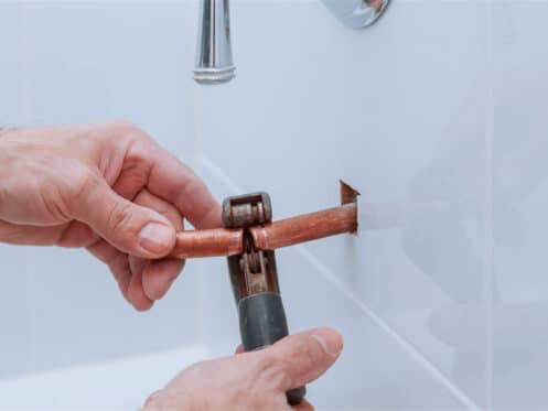 Pinhole leaks in copper pipes from hard-water pitting corrosion, with blue-green staining on a Coppell supply line