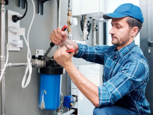Plumber installing a whole house water filtration system in a Dallas TX home at the main supply line.