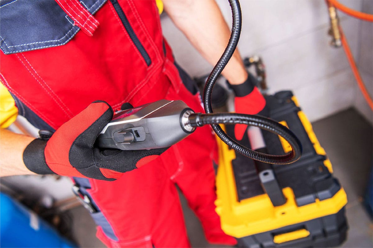 Plumbing technician using inspection camera to detect signs of a water leak in Plano home