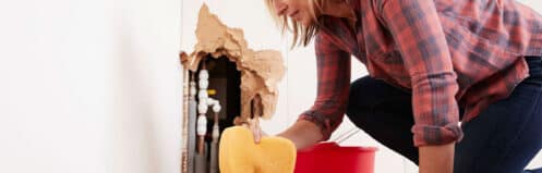 Homeowner cleaning up water damage from a hidden water leak in a Dallas home wall