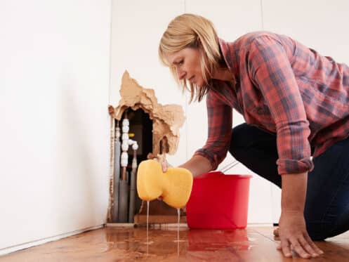 Homeowner cleaning up water damage from a hidden water leak in a Dallas home wall