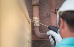 Plumber using an acoustic listening tool for slab leak detection Dallas homeowners trust, checking for signs of a slab leak near an exterior line.
