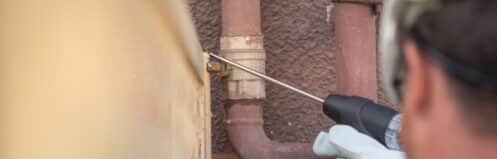 Plumber using an acoustic listening tool for slab leak detection Dallas homeowners trust, checking for signs of a slab leak near an exterior line.