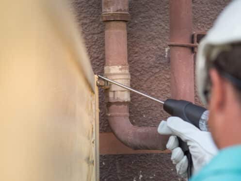 Plumber using an acoustic listening tool for slab leak detection Dallas homeowners trust, checking for signs of a slab leak near an exterior line.