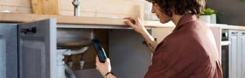 Garland homeowner documenting under-sink pipes to check for water leaks in the home
