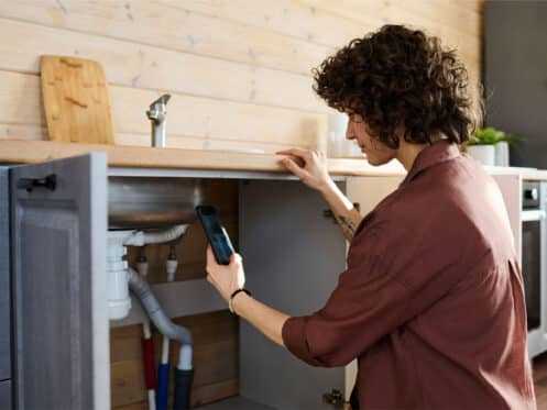 Garland homeowner documenting under-sink pipes to check for water leaks in the home